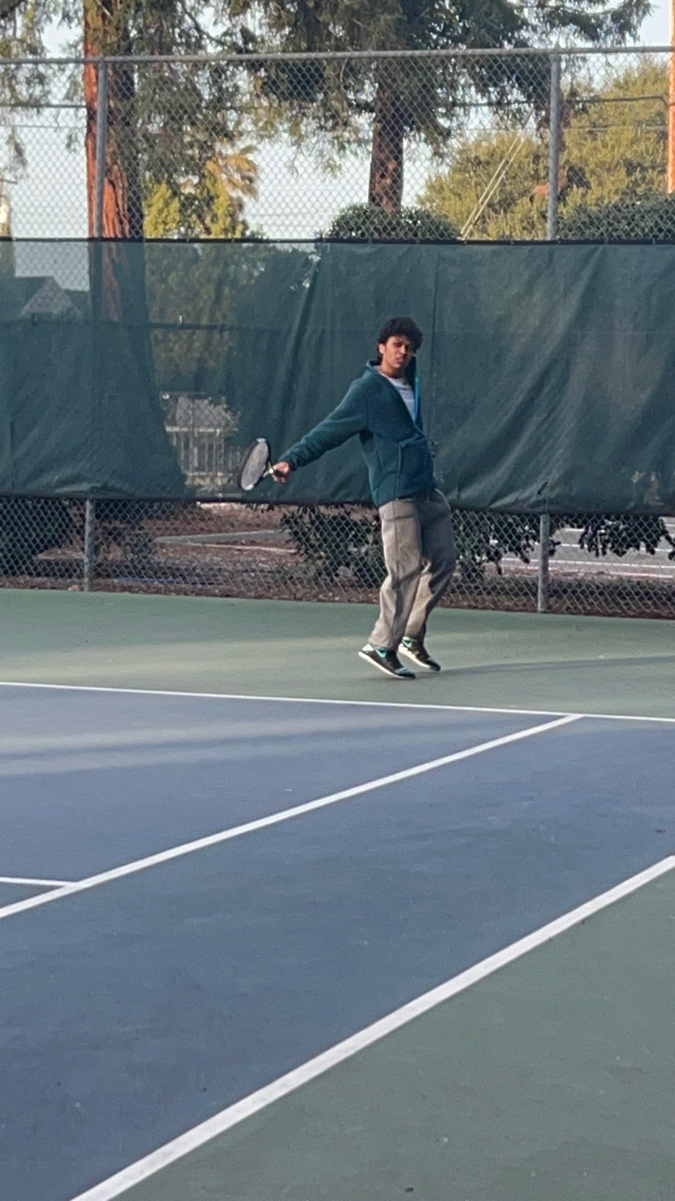 R Academy coach mid-forehand on a Bay Area tennis court